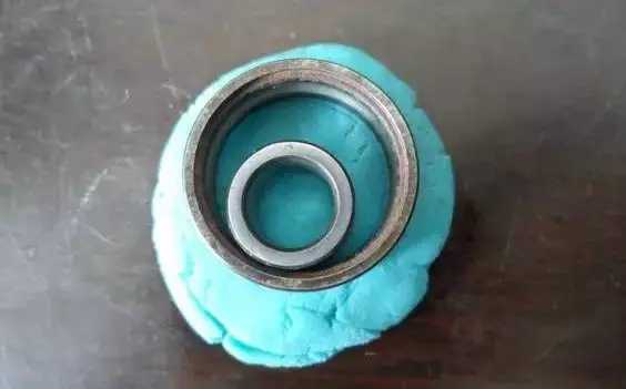 將深溝球軸承的內(nèi)外圈放到橡膠泥上,輕輕地按進(jìn)去一點(diǎn)